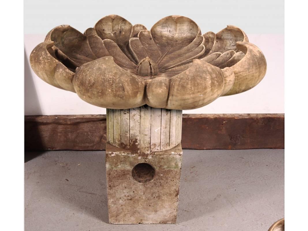 A vintage stylized lotus fountain in carved marble. Very dramatic form in very good condition with some minor chips and one old repair. The fountain has a very desireable all over patina. The two-part cast stone base is meant for the lower square to