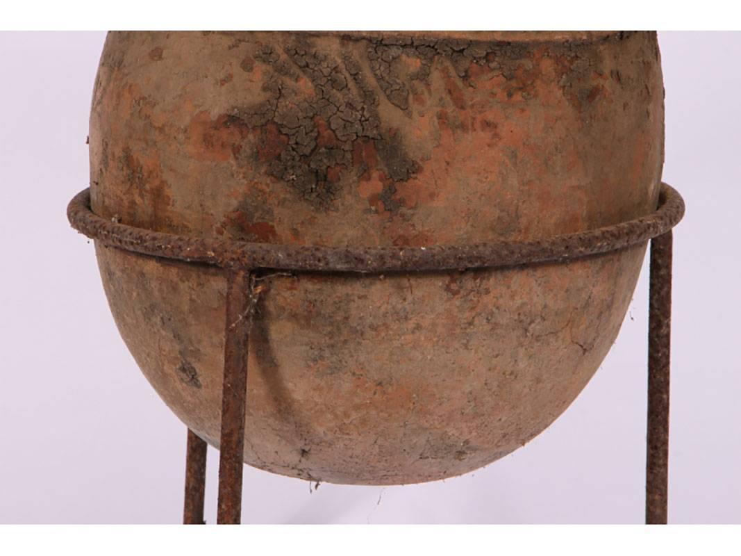 Unglazed terracotta having twin ringed handles and a double ribbed collar, the whole resting on a wrought iron tripod base.
Condition: Good, consistent with age, earthen crustrations.