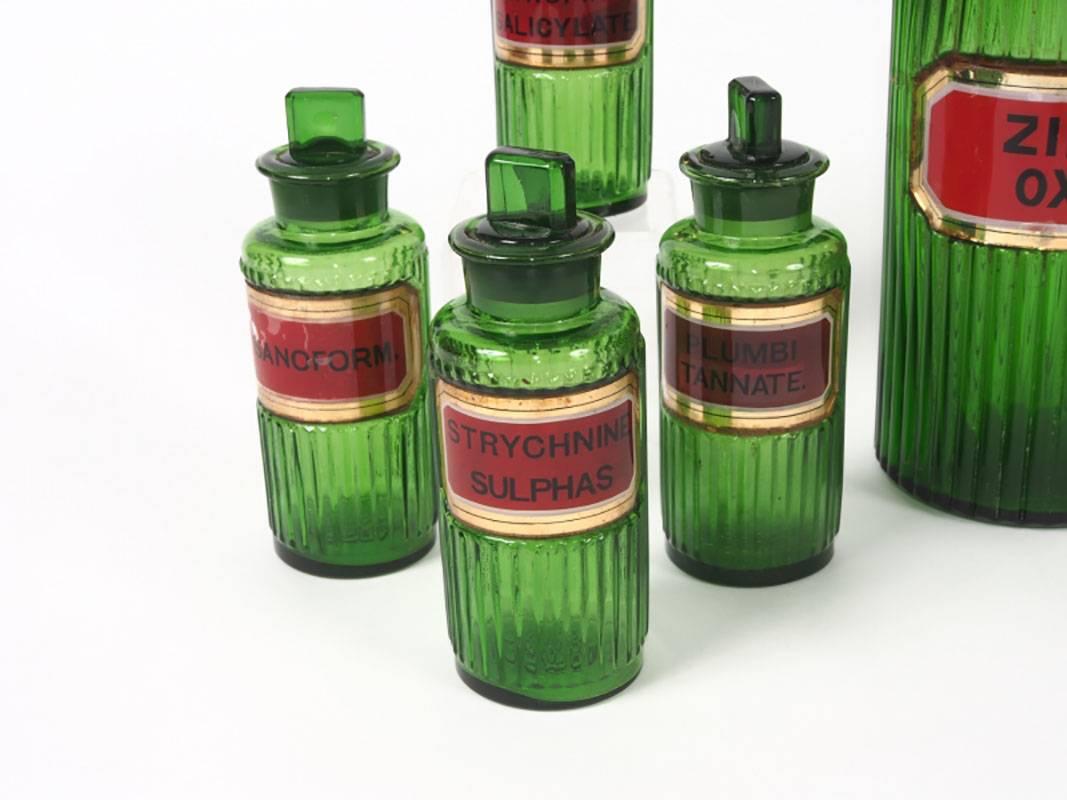 A rare group of ten 19th century green glass apothecary bottles with stoppers and gilt edged labels affixed by wax. Various labels indicate oxalic acid, Sanoform, Cocaine Hydroclorate, etc. Two large bottles measure 9