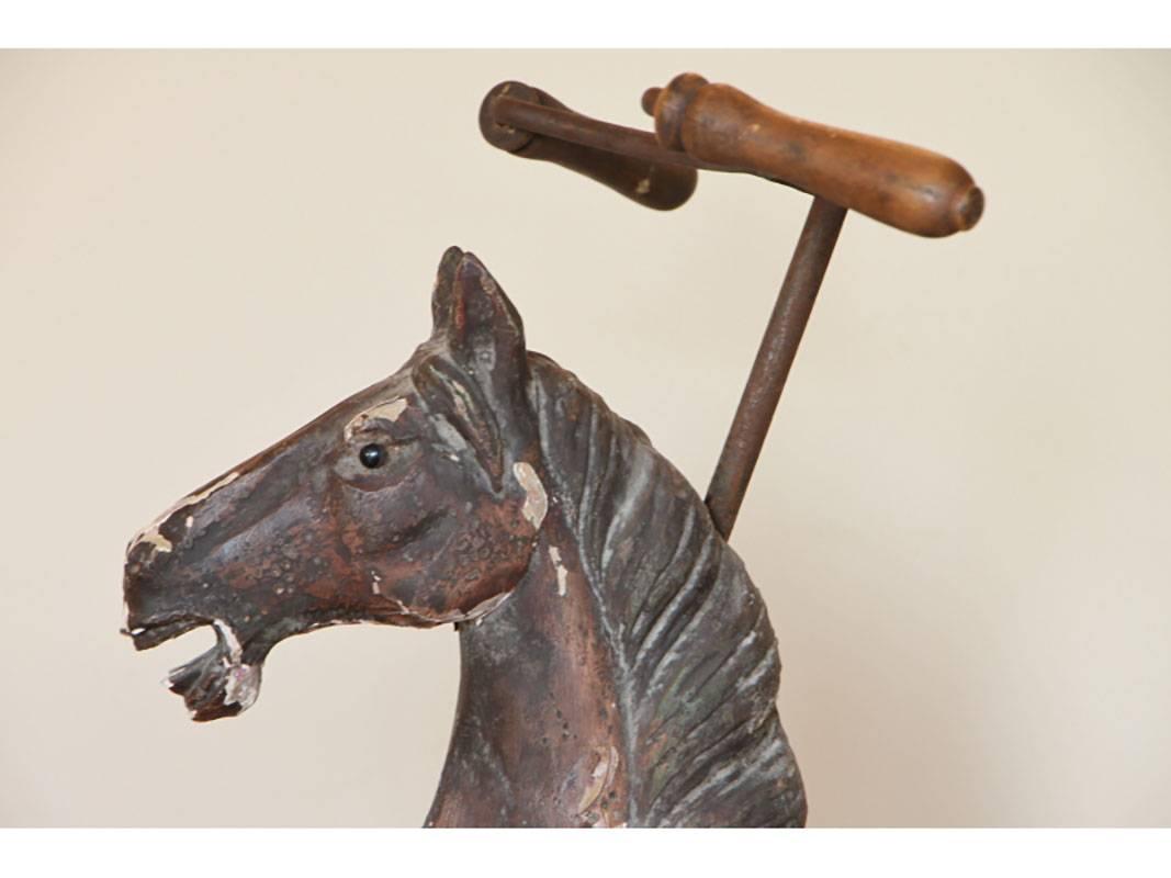 Antique Folk Art horse form tricycle with paint decoration having rustic iron frame, wood handles. Condition: One stirrup broken off and included, repair to front leg, flaking paint; consistent with age. Working condition.