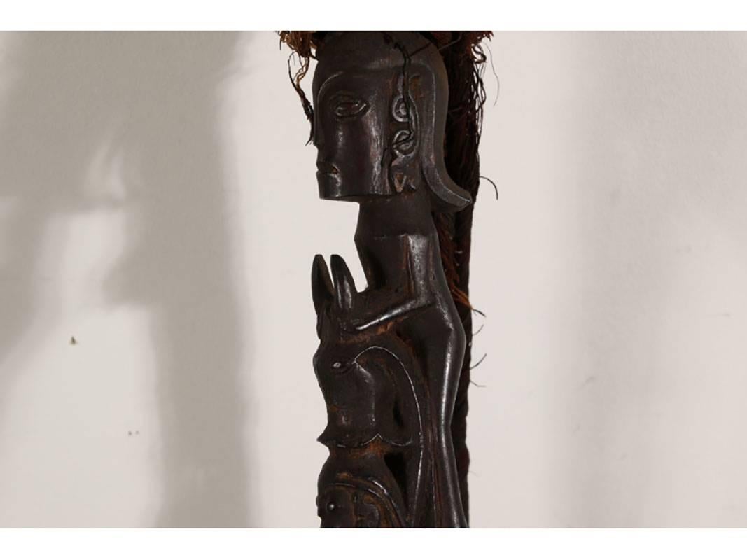 Carved figural staff showing figures kneeling and standing culminating with one larger figure at the top. The top is feathered and tasseled. Additionally, the staff tapers to a point and the lower portion carved with parading animals.
Condition:
