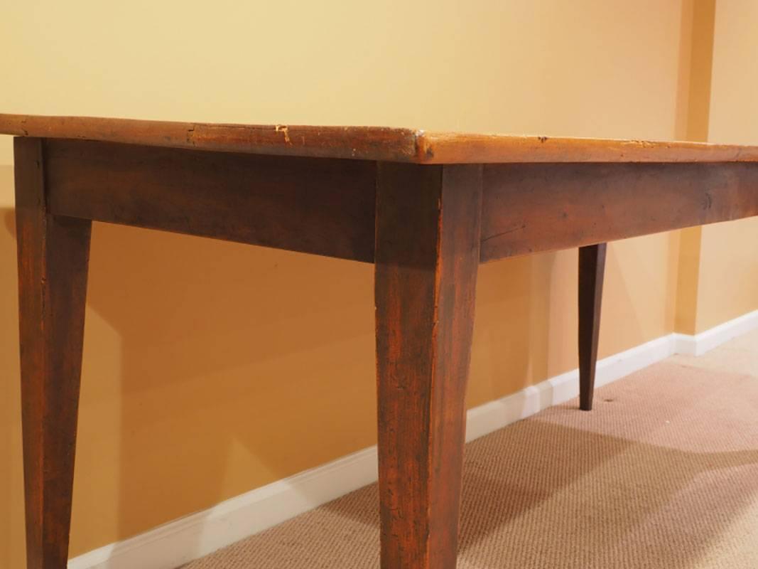 Classic antique French farm table with three board cherry top and tapered legs. The base is in a contrasting darker stain. There is some minor worm holing on the top and some old repairs to two of the legs (age crack repairs) which do not detract.