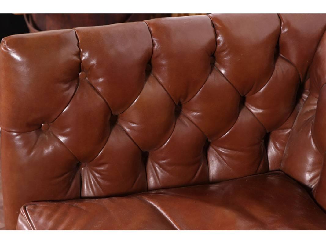 Leather sofa having button tufted surround, single seat cushion, stretcher base, brass button trim.
Condition: worn in some areas.
 