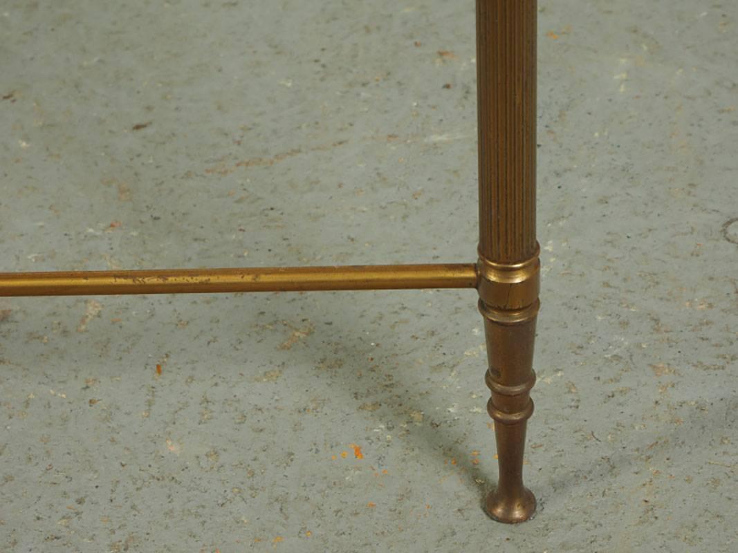 Rectangular brass cocktail table with smokey glass top having a gilt reverse band, H-form stretcher base, fluted legs and resting on dainty tapering pad feet.
Condition: Some loss to the mirrored band, consistent with age.