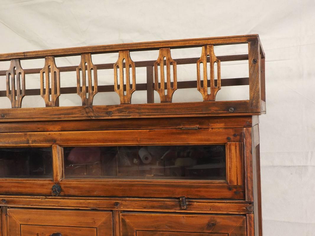 Fitted with 24 small drawers, many with interior dividers. Glass upper section. Top has carved gallery surround. Minor age appropriate wear which doesn't distract.