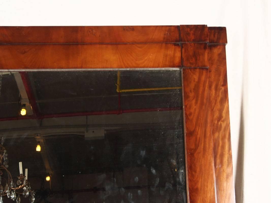 Un design en escalier en ronce de bois avec une corniche au sommet et un panneau en retrait avec un miroir ovale au-dessus du haut miroir en deux parties. Une étagère avec un ovale inséré en bois foncé a des supports à volutes avec des ovales