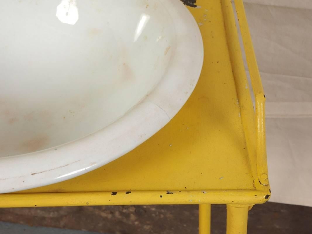 A yellow paint decorated metal washstand with semi-vitreous porcelain bowl. The metal rack has two tiers with side towel racks, top gallery and all raised on metal bun feet.
Measurement: Bowl 16.5