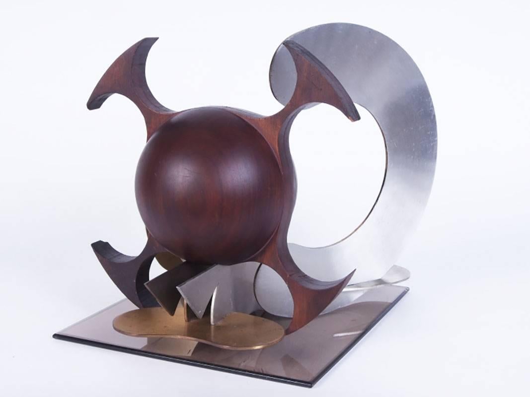 Multi-media sculpture with six pieces brass, aluminium and wood presented on an acrylic base. The sculpture resembles a puzzle-esque sculpture with a wood Sputnik with slots mounted on the metal. Unsigned work.
Condition: Four chips to the ends and