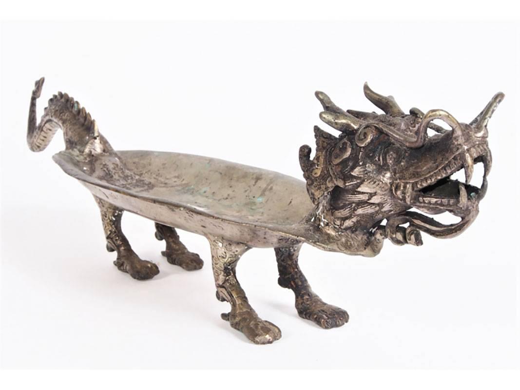Brass figure of a dragon with openwork, oval form bowl, spiked tail and raised on paw feet.
Condition: Lacking flame on one side, verdigris and stains to the inside bowl; lacking spike on back of front foot.