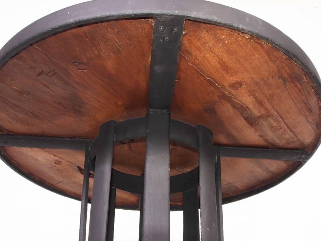 Bar table comprising of re-purposed wood top with iron trim over an open wrought iron base with quad feet with tapering column.
Condition: good.