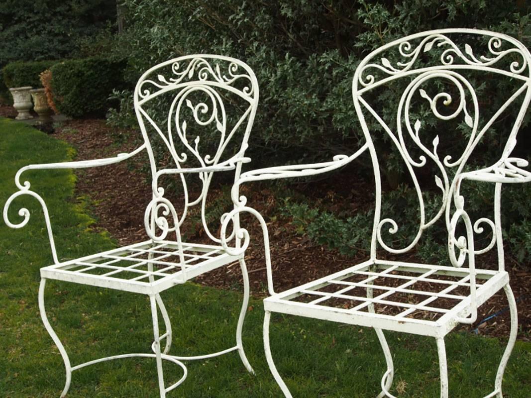 Wrought iron with openwork scrolled leafy vine motifs on curvilinear arms, legs and backs. In white paint.
Condition: Overall very good, some expected wear to the paint.