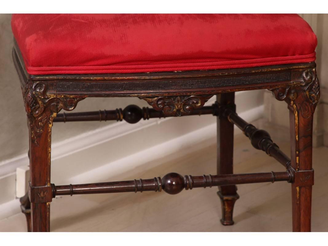 Probably English, circa 1860, elaborately carved rosewood, the top rails with scrolled ends and mask terminals, the frames carved in dentated scallops. The seat rails have carved scrolled elements in the centers, raised on legs with carved knees