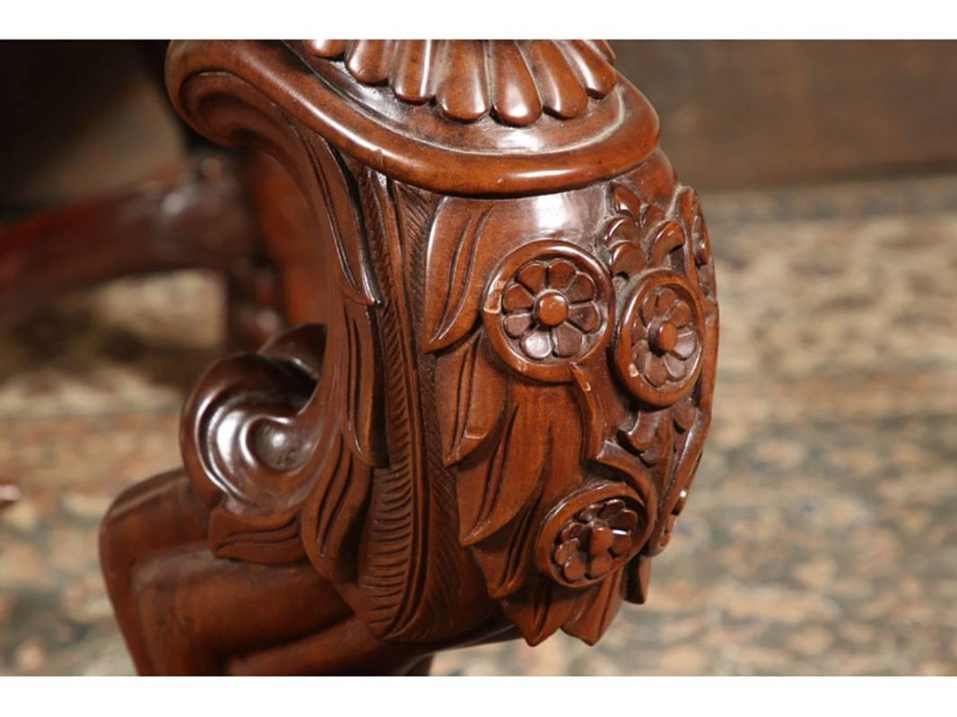 Rectangular carved mahogany table with a lattice form openwork apron. The heavily carved lion form legs with acanthus leaf tops, floral and leaf details and scrolled backs. The stretchers with C shaped sides and turned and reeded central bar with