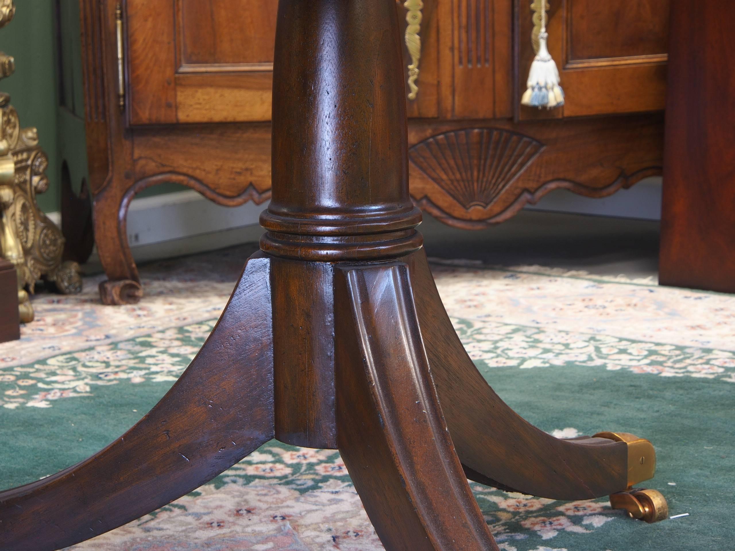 Fine Classic flame mahogany dining table with two leaves. Brass capped castered double pedestal base. Slight scratches to surface, but still very nice.