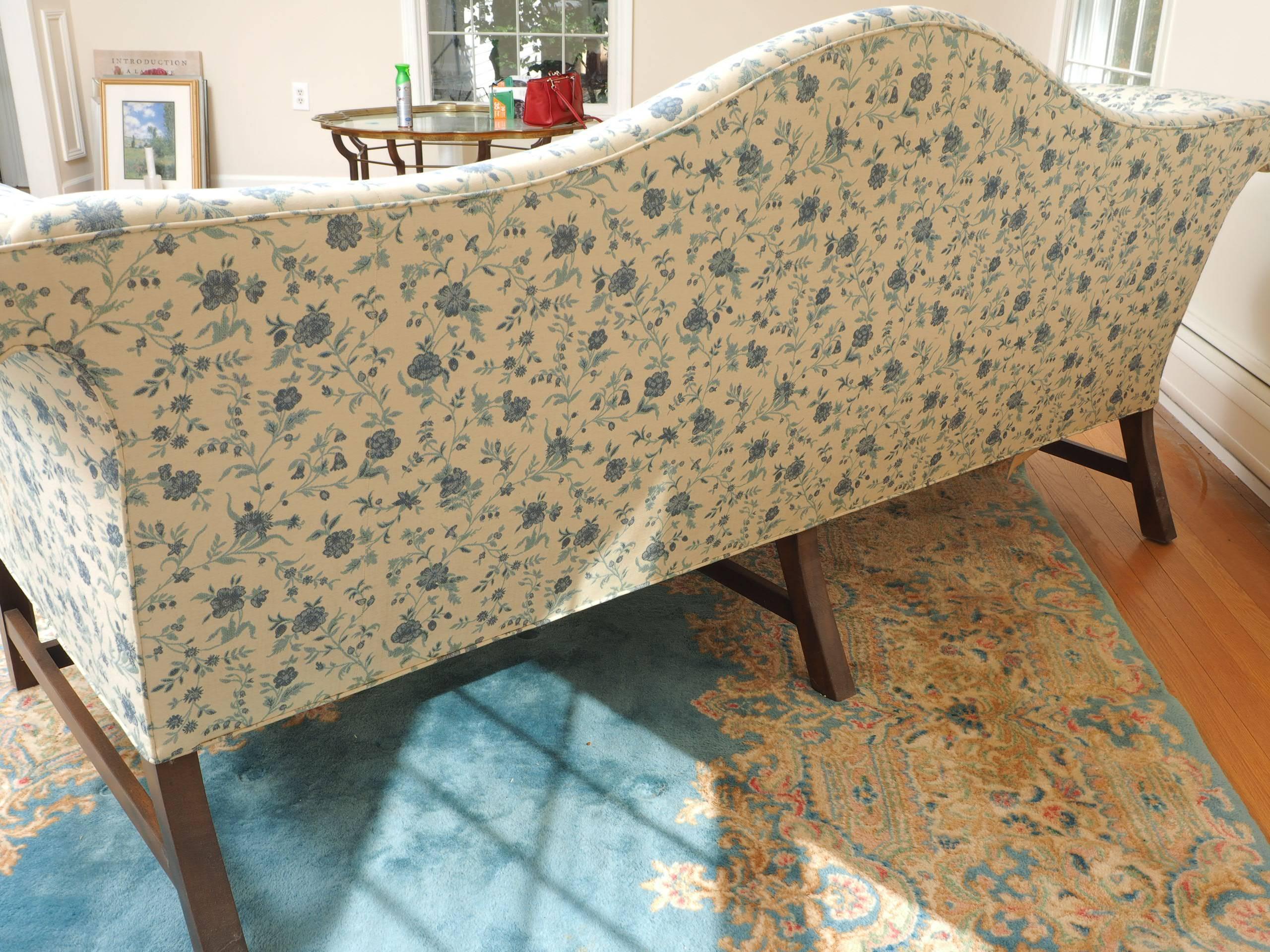 George III style with scrolled arms, square front legs and square splayed back legs with an H stretcher. Upholstered in a blue on cream floral print. 
Condition: good, some stains to upholstery, some wrinkling to the tops of the arms.