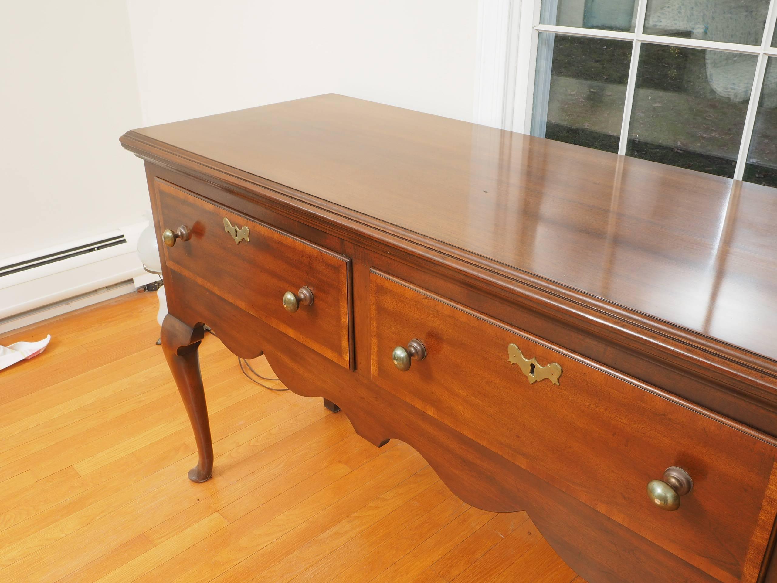 Fine mahogany with carved top molding, the apron with cross-banded drawers with brass pulls and escutcheons. With a scalloped frieze on front and sides, and recessed side panels. The whole raised on shaped cabriole legs in front and squared back