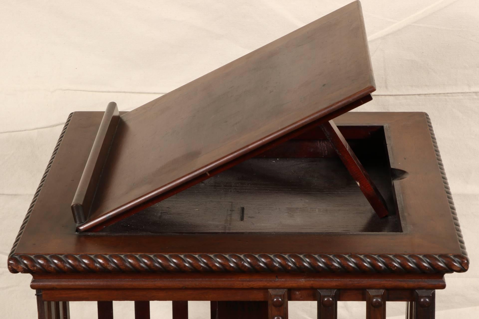 Two-tier antique rotating case features slatted side runners, carved rope edging, a flip-up book stand and castered feet. Original stamp remains; Trade Mark Danner (?)
Condition: Missing runner on one side, and another runner shows damage.