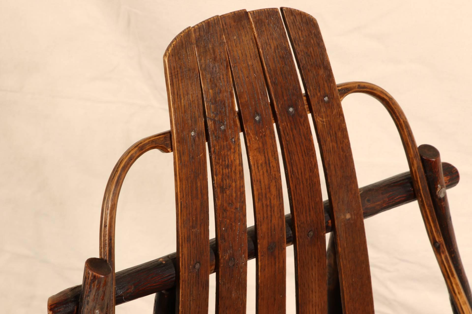 Mixed wood in a fine patina with shaped oak slat back and seat. The frame constructed of twisted and turned thin branches. Mounted on an oak rocker base. The seat rail with an incised vine motif.
Condition: Very good with age/wear consistent with