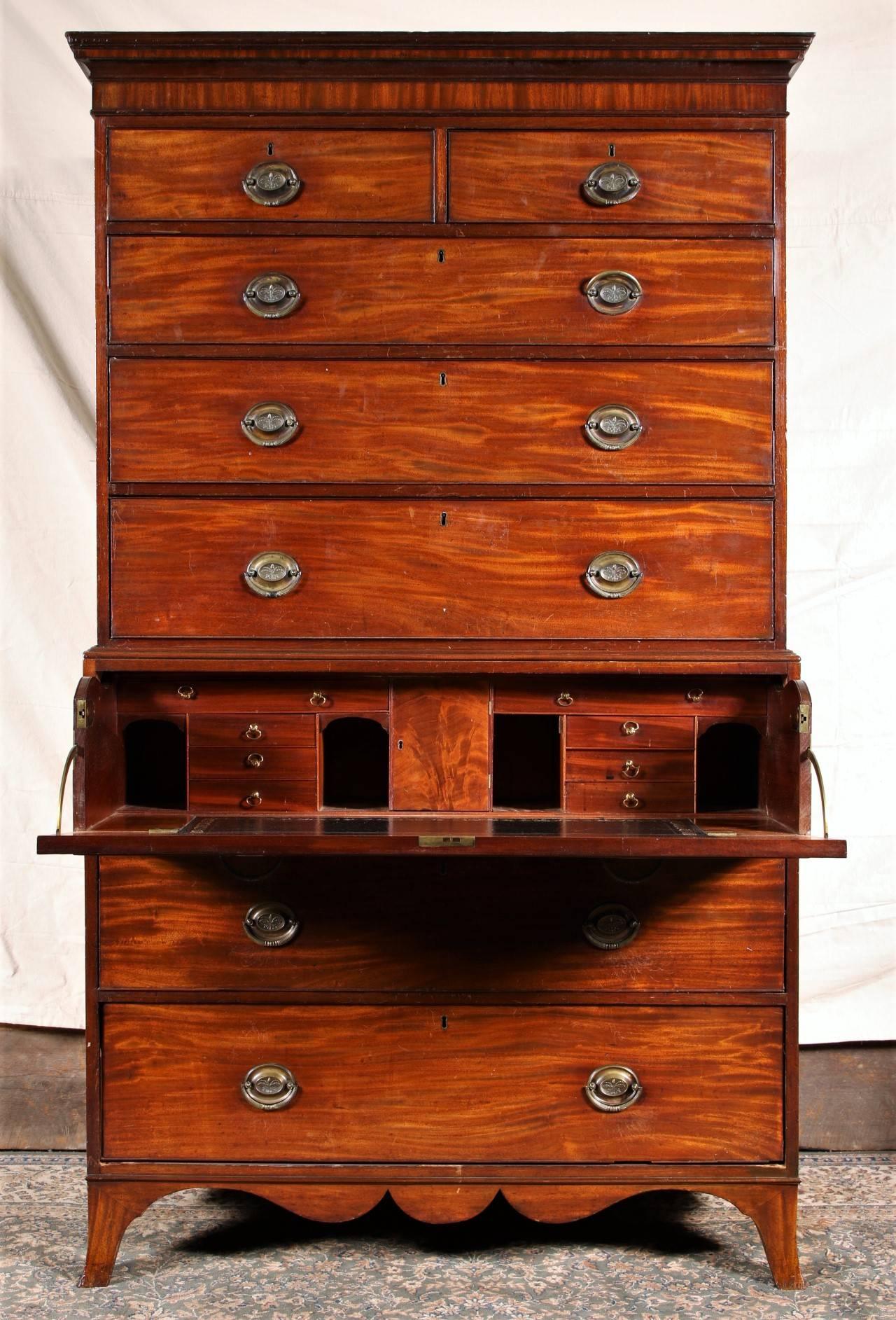 Mahogany two over six drawers, bold reeded brass pulls with oak leaf and acorn casting, brass escutcheons, scalloped apron and resting on bracket feet. The interior is fitted with a central door and flanked by pigeon holes and shallow drawers. The