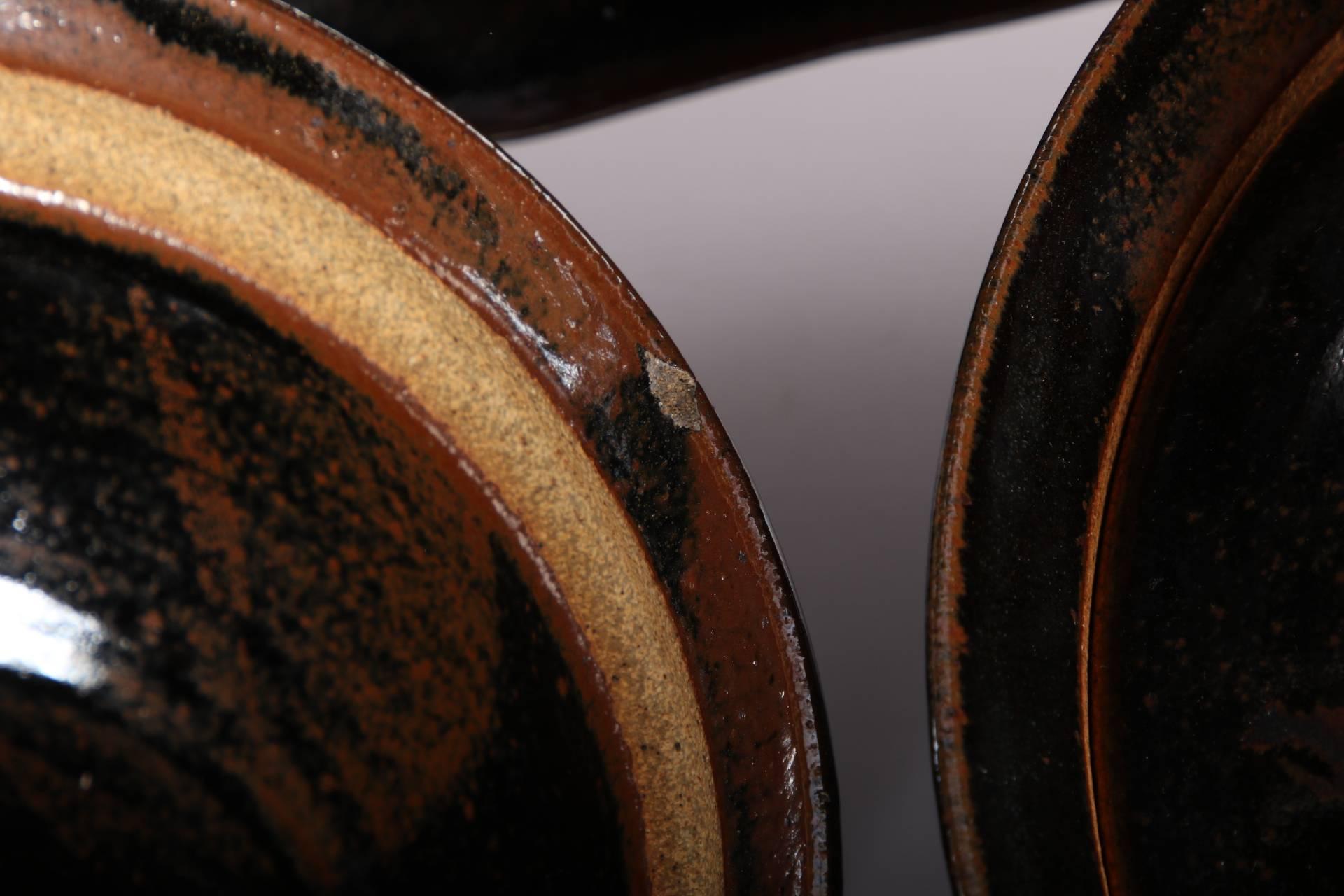 Groupe de poteries Malcolm Wright comprenant deux bols couverts et un chargeur surdimensionné. Tous les monogrammes sont signés sur les bases non émaillées. Tous en glaçure noire et brune et décorés de motifs de feuilles. Le chargeur a un bord