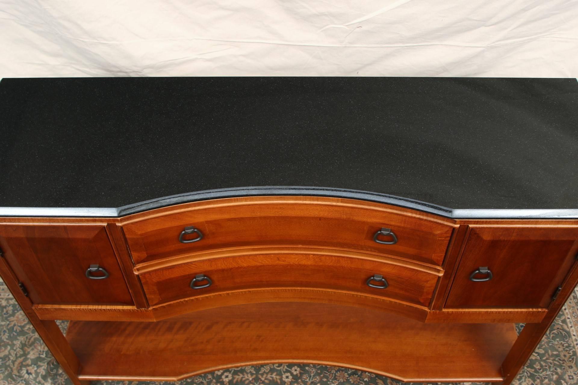 Mahogany with a shaped front and gray granite top with bullnose border. The cabinet with two side compartments flanking two long center drawers and a lower shaped shelf. Raised on front legs with canted corners and square back legs. Very well made,