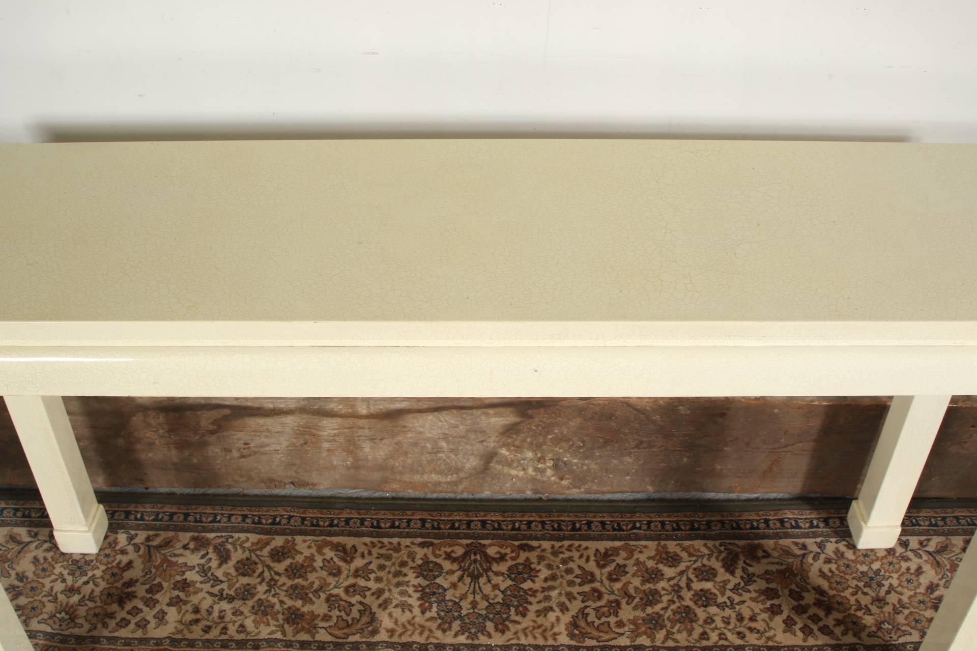 A modern console table in a cream crackle pattern laminate finish, the top over an inset apron, raised on tall legs with Chinese style block feet. 
Condition: Very good with a few chips to the laminate.