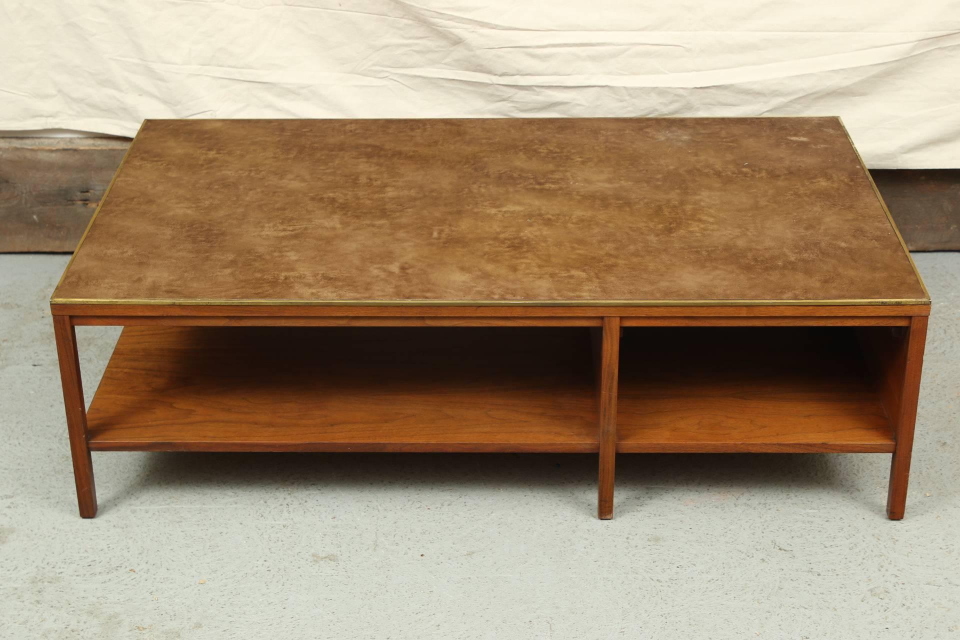 For Calvin. Walnut two-tiered table with a lacquered mottled brown leather top with brass banding. The lower tier in two sections with a single drawer with gray metal pulls on the solid side, and a slightly recessed top band with inset square