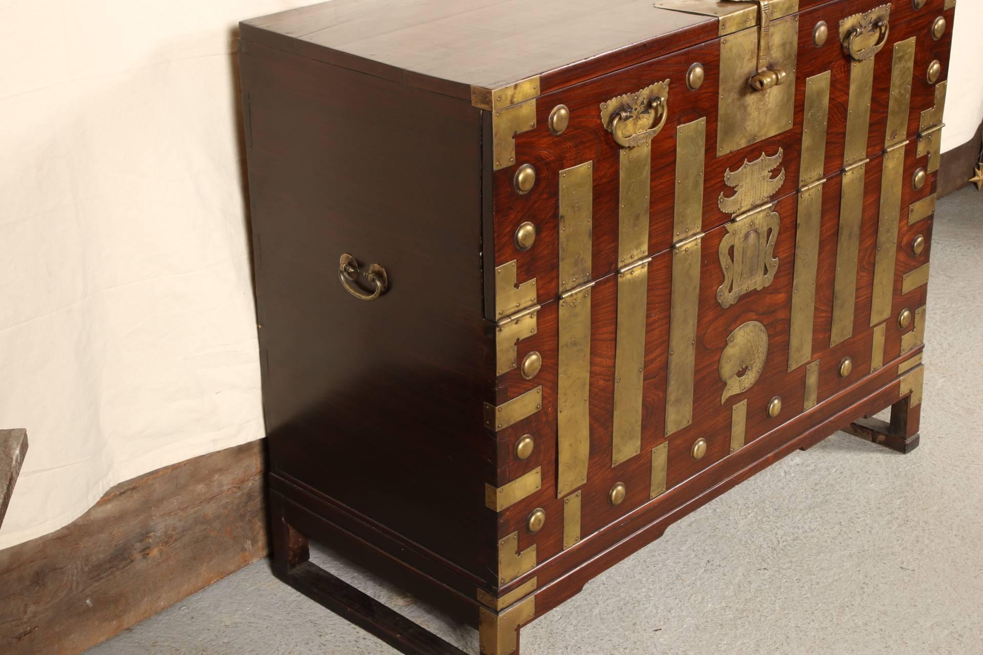 With heavy brass incised fittings. Three planks on the top with a heavy centre latch. A hinged drop down front panel with two brass handles. The centre front with brass pagoda and fish attachments. The entire front decorated with incised panels