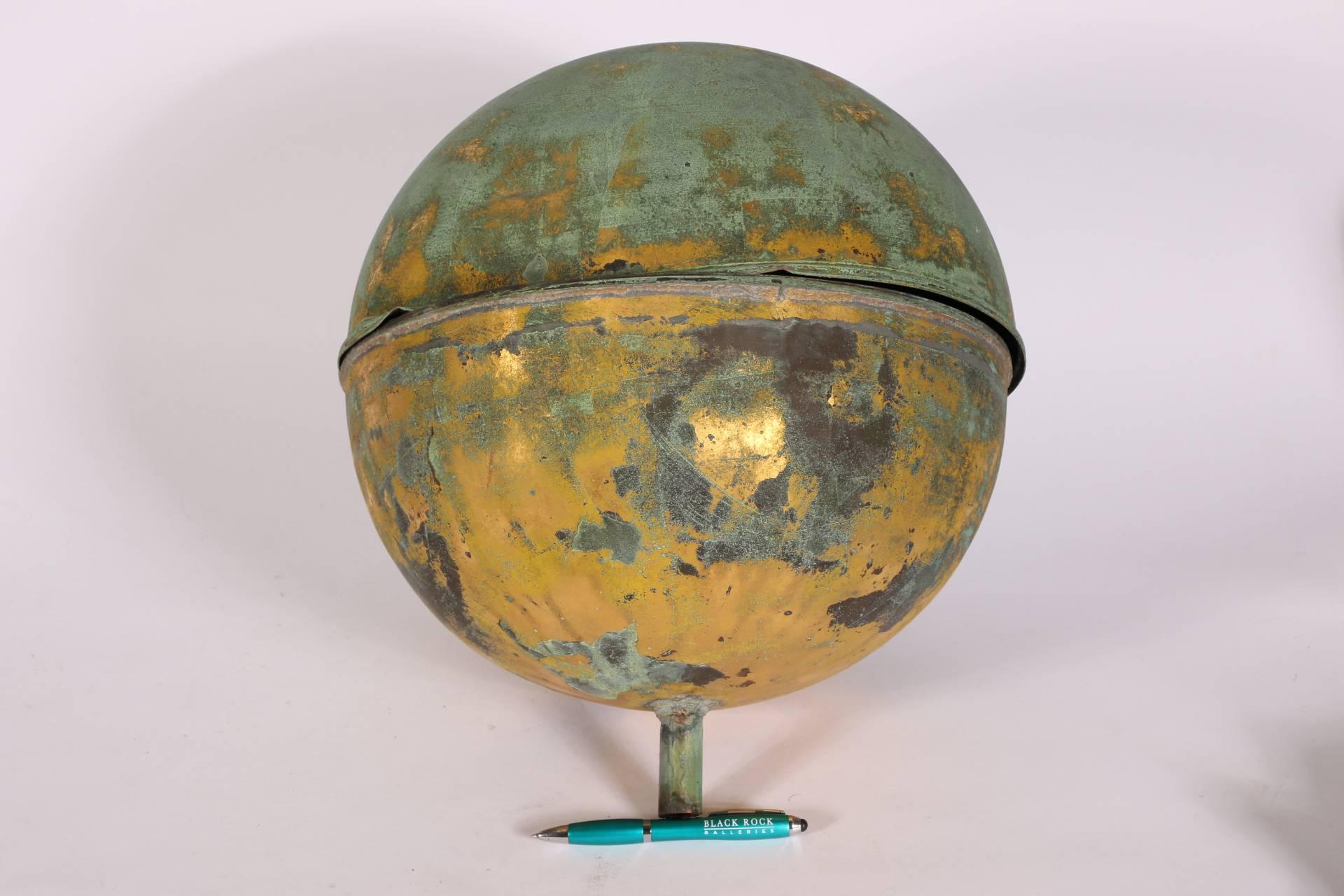 Globe form made in two parts, with a hollow stem for attachment on the base. 
Worn gilt, patches of green patina overall, separation around the center seam, ding, all as expected with use.