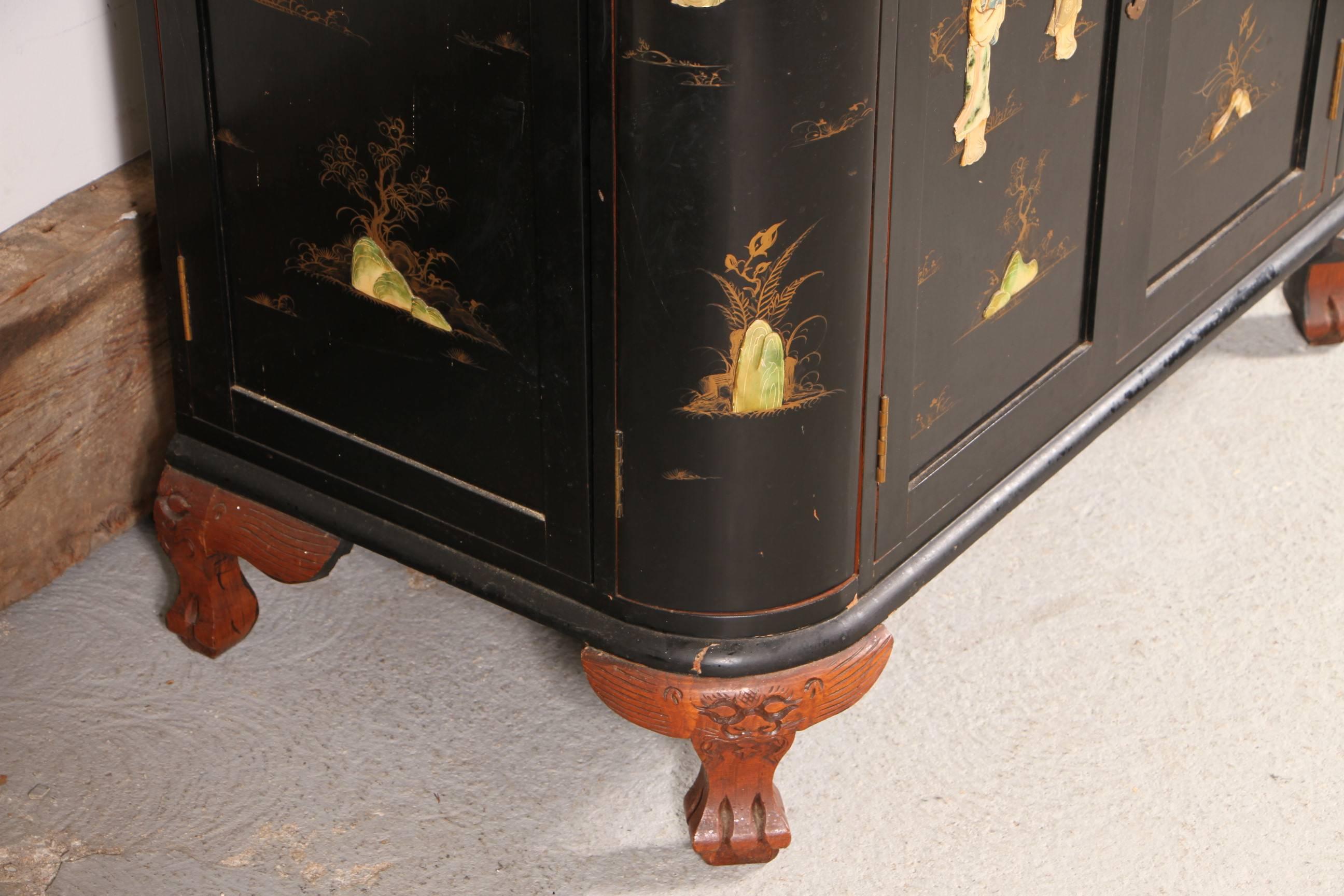 The ebonized chinoiserie cabinet, elaborately decorated with mother-of-pearl and polychrome stone inlaid figures, landscapes and gilt embellishments. With unusual rounded corners and the contrasting carved paw feet.
The top lifts up and the door
