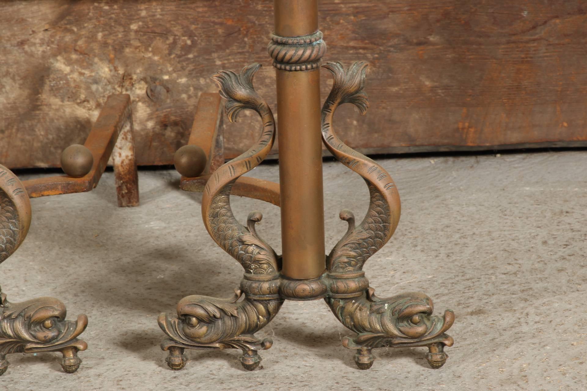 Tall reddish brass rods with intertwined dolphins on top and curved dolphin feet on each side. With iron rods at back. In a nice patina.
Condition: Some tarnish, rust to the iron.