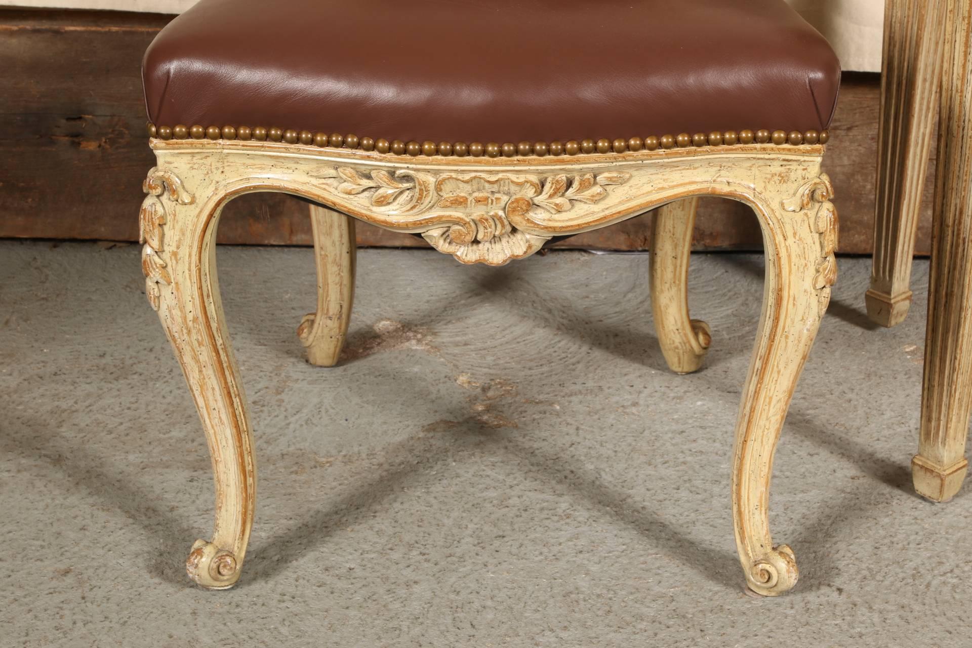 By Auffray & Co. Louis XVI style desk in cream paint with carved shaped apron with foliate decoration, raised on tapering square reeded legs. Along with a Louis XV style side chair in cream paint with carved foliate decoration and brown leather seat