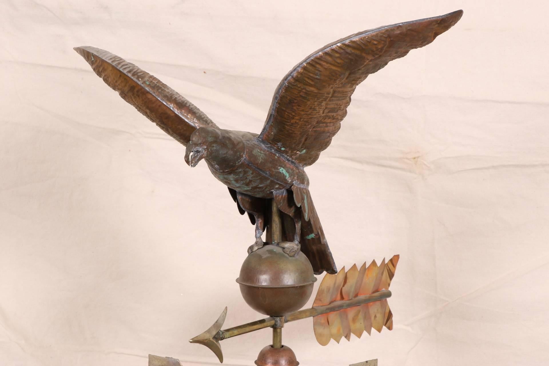 The copper eagle alighting on a sphere on top of a copper and brass arrow, above the cardinal points in gilt paint. Raised on a black painted and mounted on a wooden X-form base.
Condition: Tarnish to the eagle and sphere, wear to the gilt.