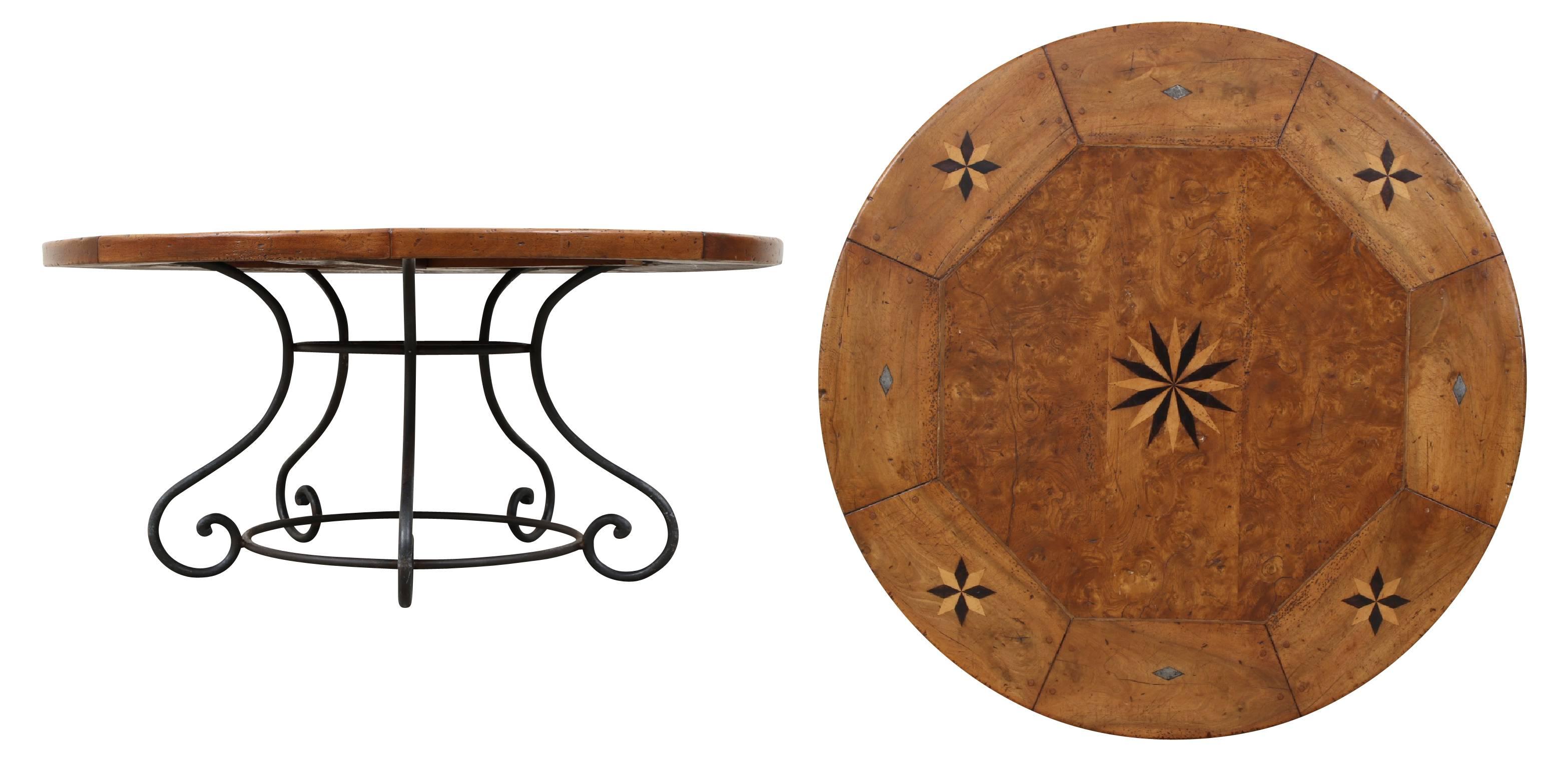 An inset burled wood octagonal top with an outer band in eight curved wood segments. The centre and four alternating band segments with inlaid star motifs in dark and light woods and metal diamond motifs in the other band segments. A newer wrought