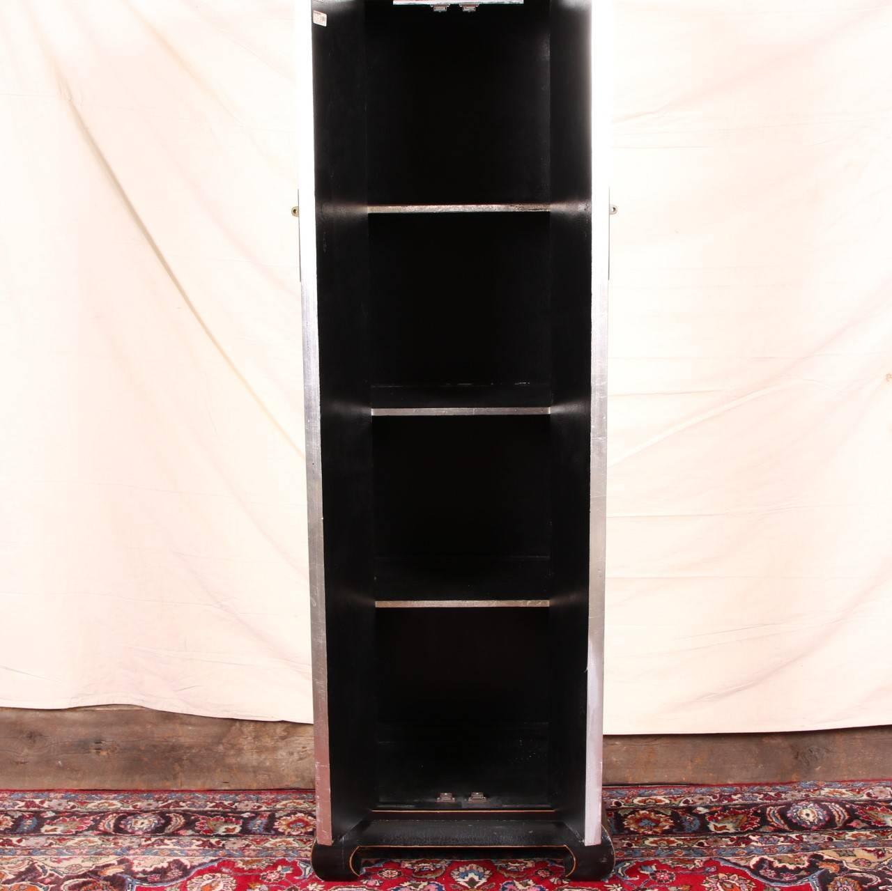 Two-door tall narrow cabinet with metal disk form lock with bolt, raised on a Chinese style ebonized base with incurved feet. Three interior shelves. 
Condition: gouge to the left door, scratches overall, crazed base surface.