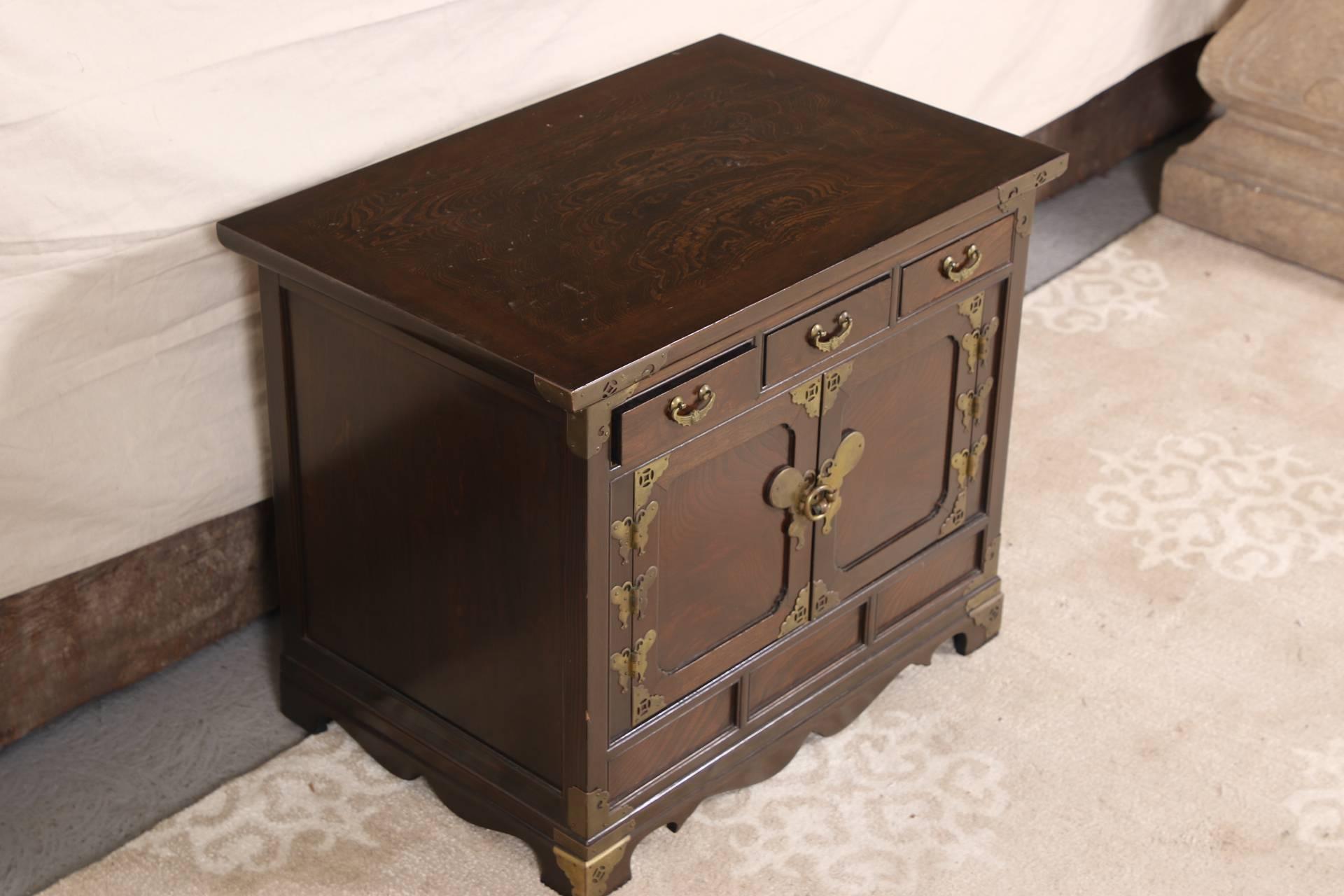 A rectangular cabinet with a banded top, three apron drawers, recessed lower panels and recessed paneled double doors. the shaped lower frame with block feet. Brass hardware on the corners and bat form pulls, door hinges, and front lock (lacking the