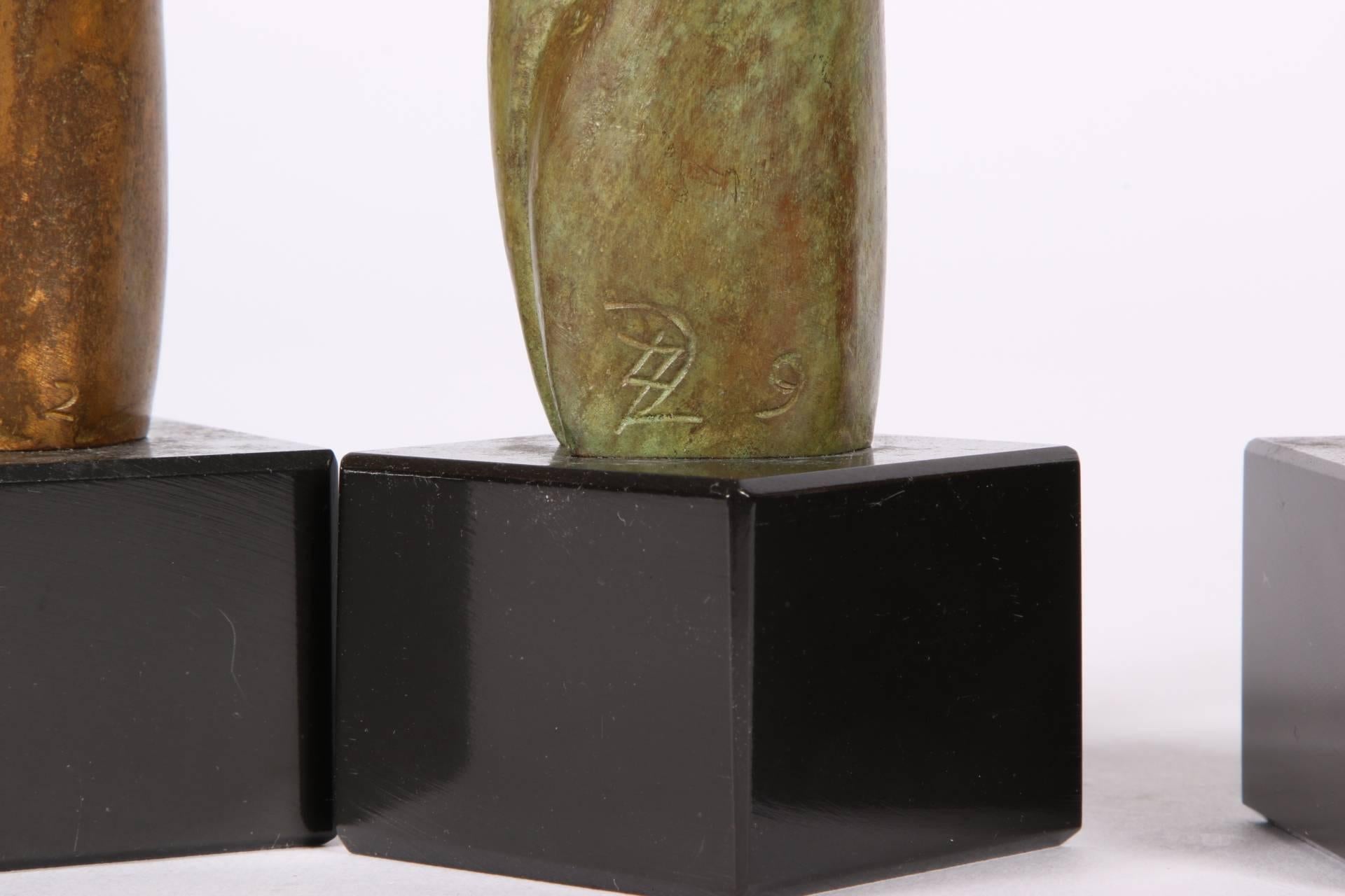 Group of three signed modern abstract bronze figures in the Manner of Henry Moore. Each a mother with child enveloped in a cloak. Two are dark bronze tone (numbered 2 and 3), one in a green/bronze patina (numbered 9). Monogrammed and numbered near