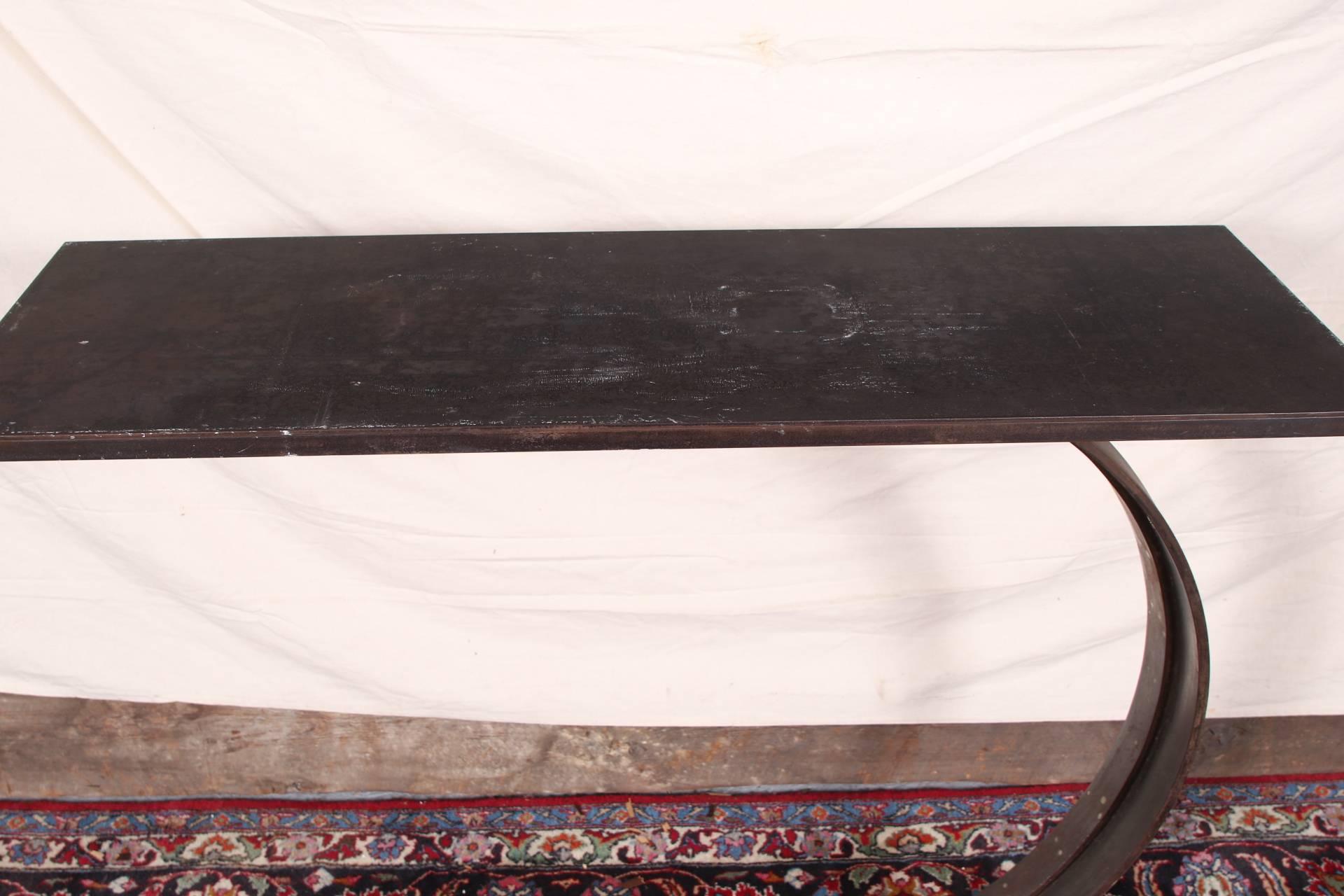 An arc supporting a rectangular top with two pierced tabs for a attachment on one long side. Mounted on a tiered circular base. 
Base diameter is 13.5 inches.
Condition: scratches to the top, some rust to base and arc