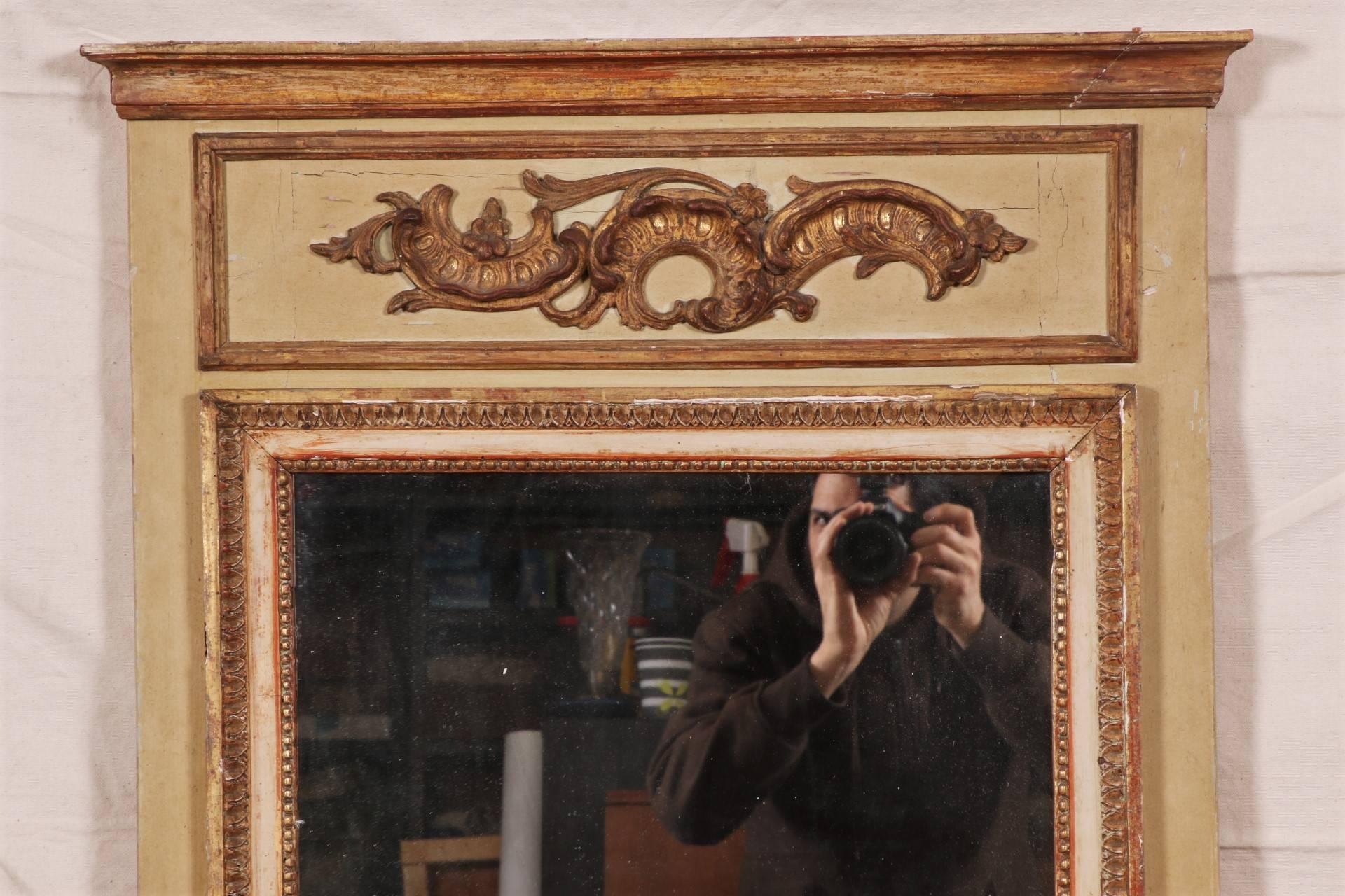 Carved, gesso, gilt and painted pier mirror. A carved top over a pale yellow painted frame with an upper panel with gilt half cartouches. The two-part mirror with a carved projecting surround in cream paint and gilt with leafy and beaded frame