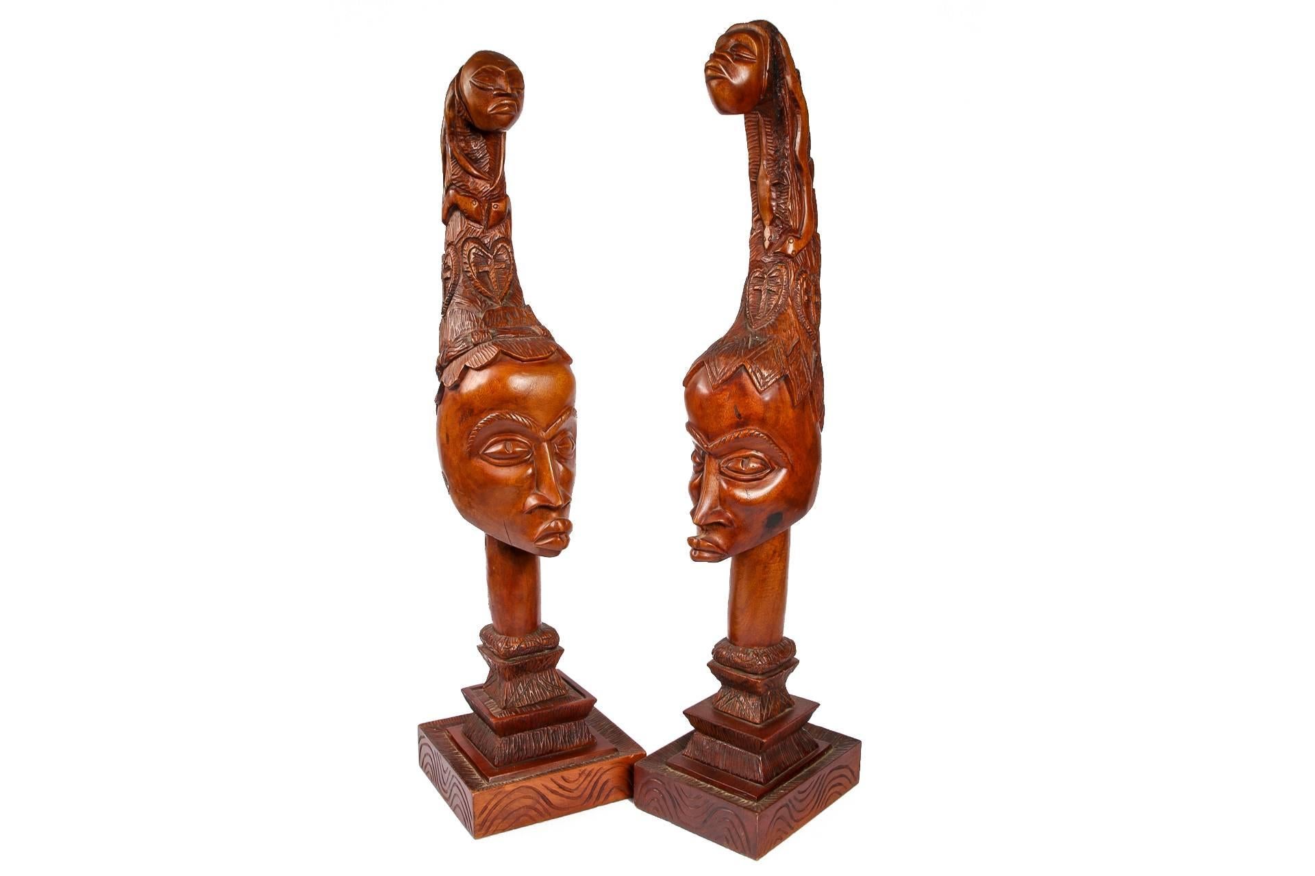 The heads surmounted with tall headdresses with figural tops and heart and cross motifs on all sides. 
The smaller of the two measures: base - 10 inches by 9.25 inches with height of 36 inches. 
 