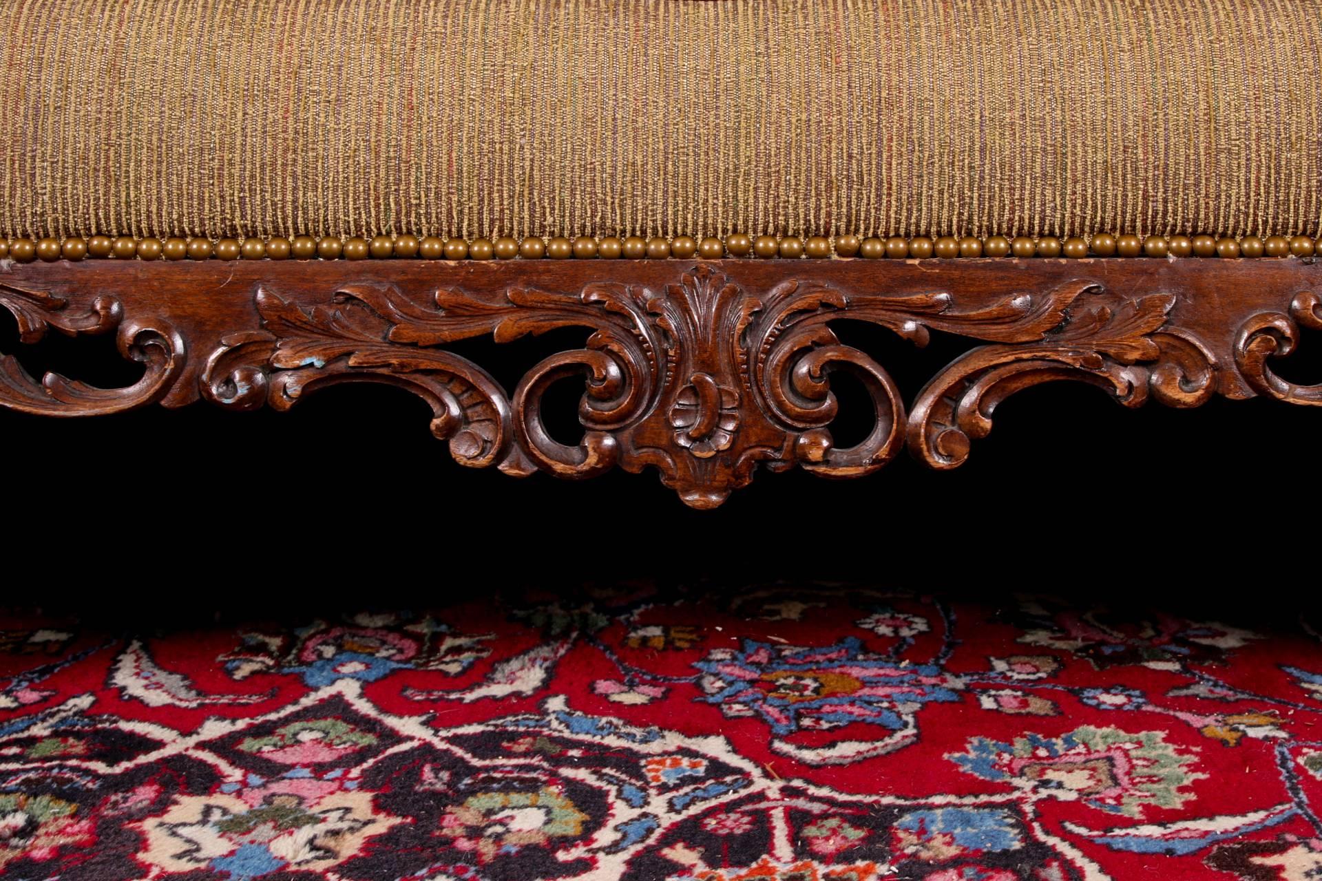 Carved wood frame with shell and scroll motifs, with a serpentine camel back upholstered in a textured tan and rust finely striped fabric and tan leather sides, back and cording. Nail heads on the sides and back. Raised on carved Spanish feet in