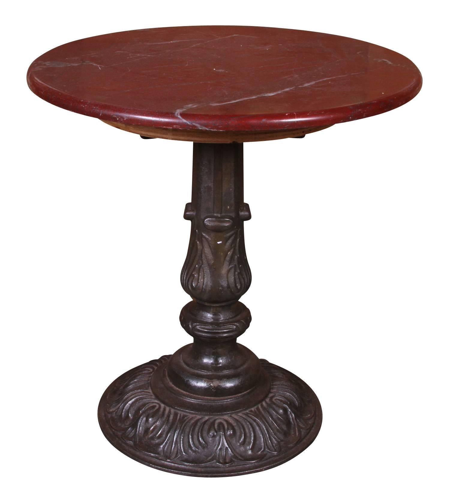 A pair of cafe tables with scrolled cast iron bases and Ox blood marble tops, once used at New York's Carlyle Hotel in the 1940s. The tables have great proportion and are very solidly made, with a beautiful overall age patina. There is some slight
