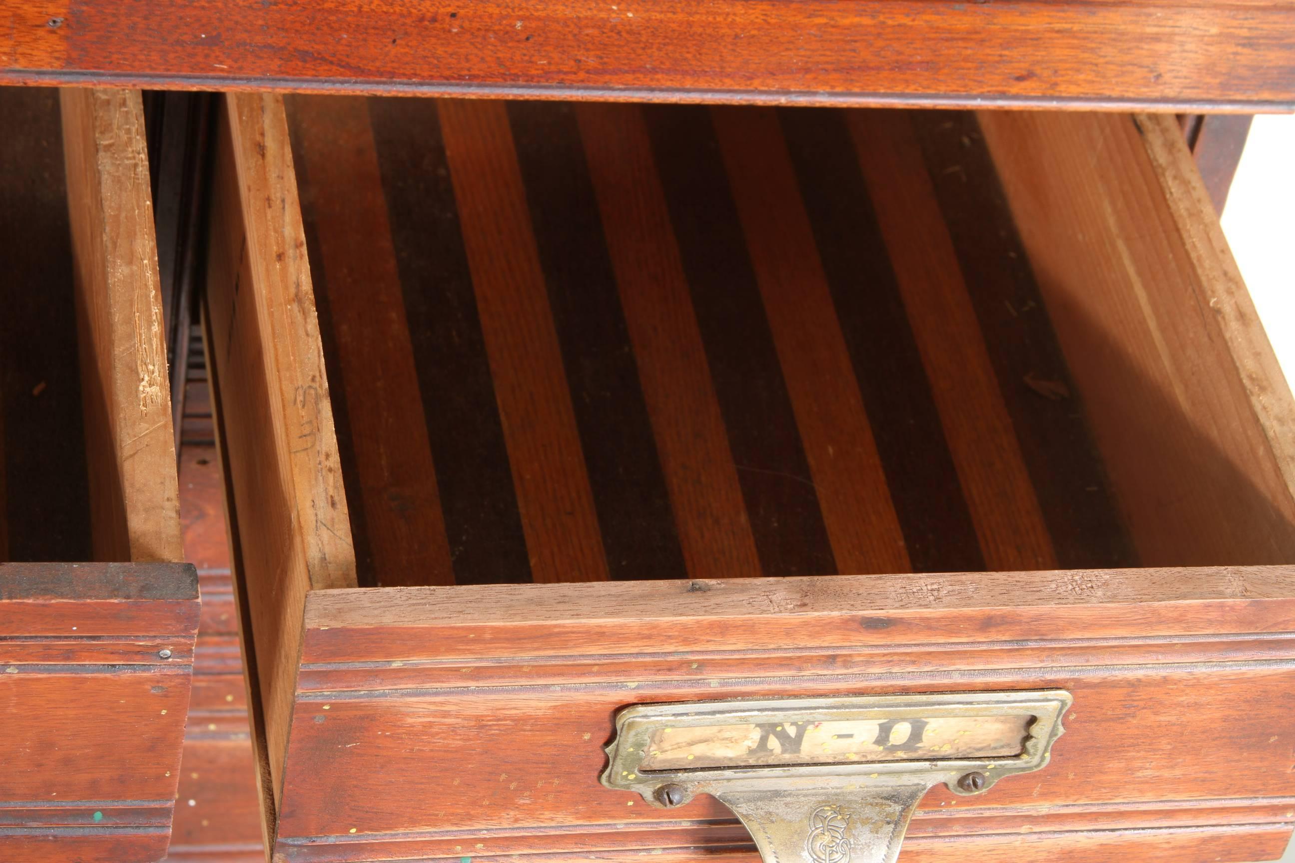 A very well made and solid 19th century apothecary type 18 drawer card file cabinet in very good antique condition. With engraved pulls having attached filing plates. The bottom right drawer is missing the upper left corner of facing.