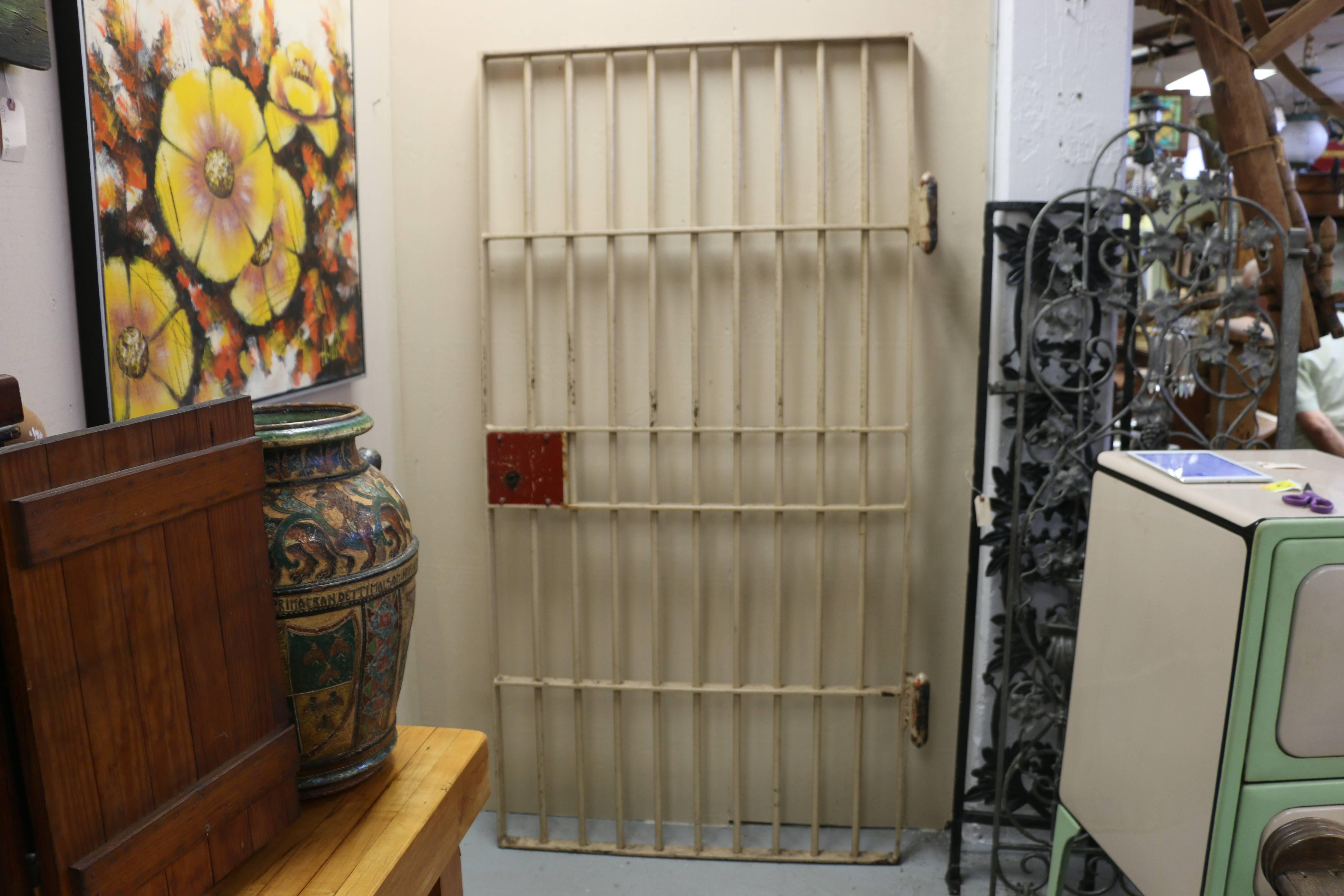 A completely authentic solid steel jail door in all original vintage condition. Very heavy with worn tan paint and red paint lock box.  Acquired in New York State. A unique and historical found object.