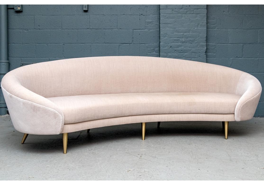 Dune Studio, New York, Galaxy à la forme incurvée, rembourrée dans un tissu en faux daim et mousse de polyuréthane sur du bois massif et reposant sur sept éléments en laiton brossé.  pieds effilés. Ce canapé a souvent été présenté dans des décors