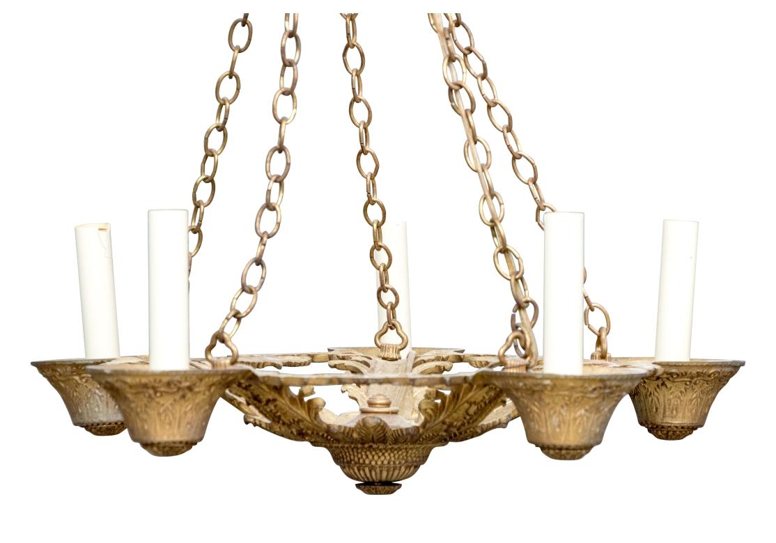 Lampadario d'epoca in metallo dorato con 5 catene sospese dalla piastra circolare del soffitto, unite a 5 bracci. Il corpo del lampadario presenta un motivo fogliare centrale e pannelli decorati con fiori a campana.

Dimensioni: 18