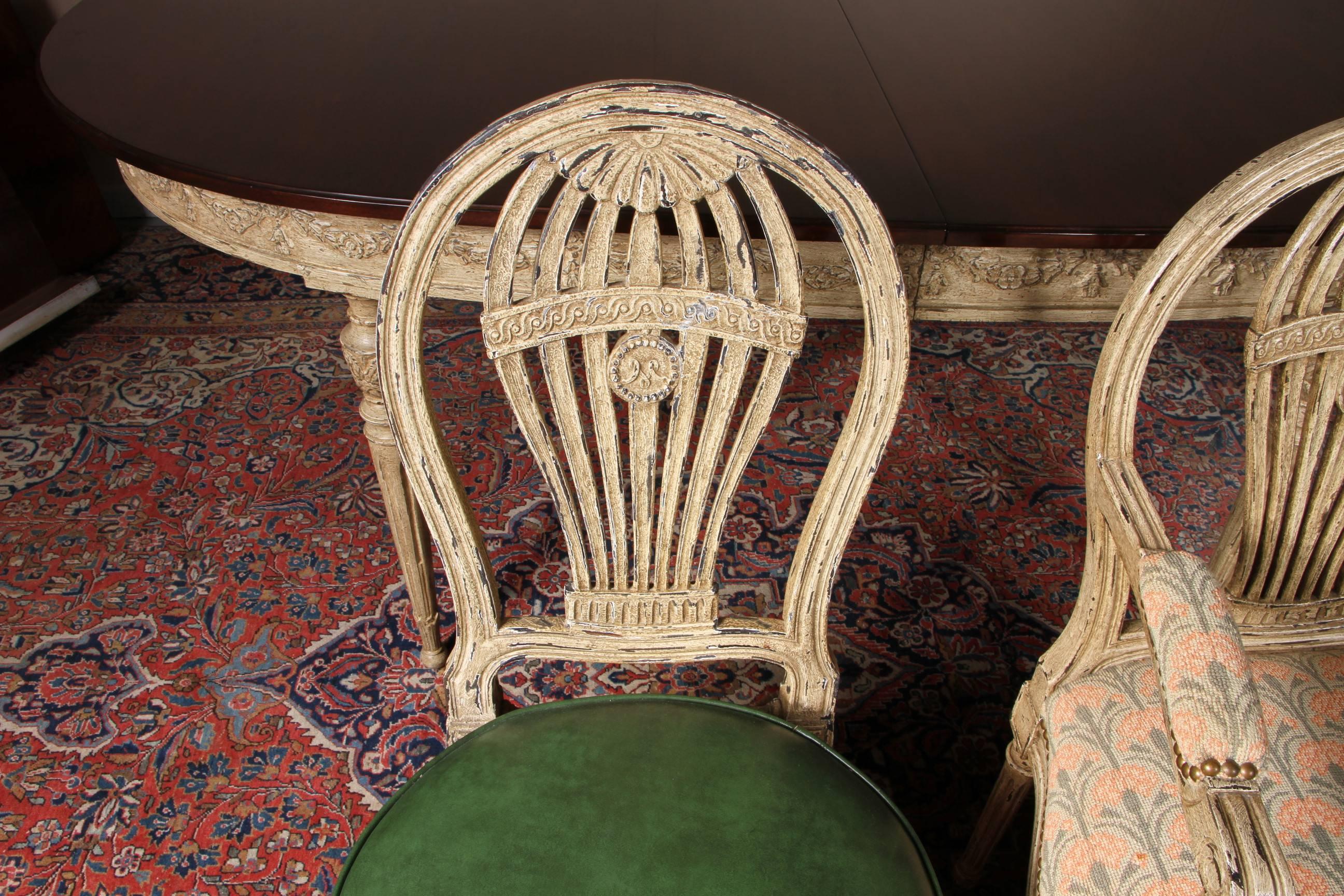 An Adams style table in a faux distressed painted finish, with oval top, garland swags on frieze, reeded, tapering, turned and carved legs ending in ball feet. Comes with two 17