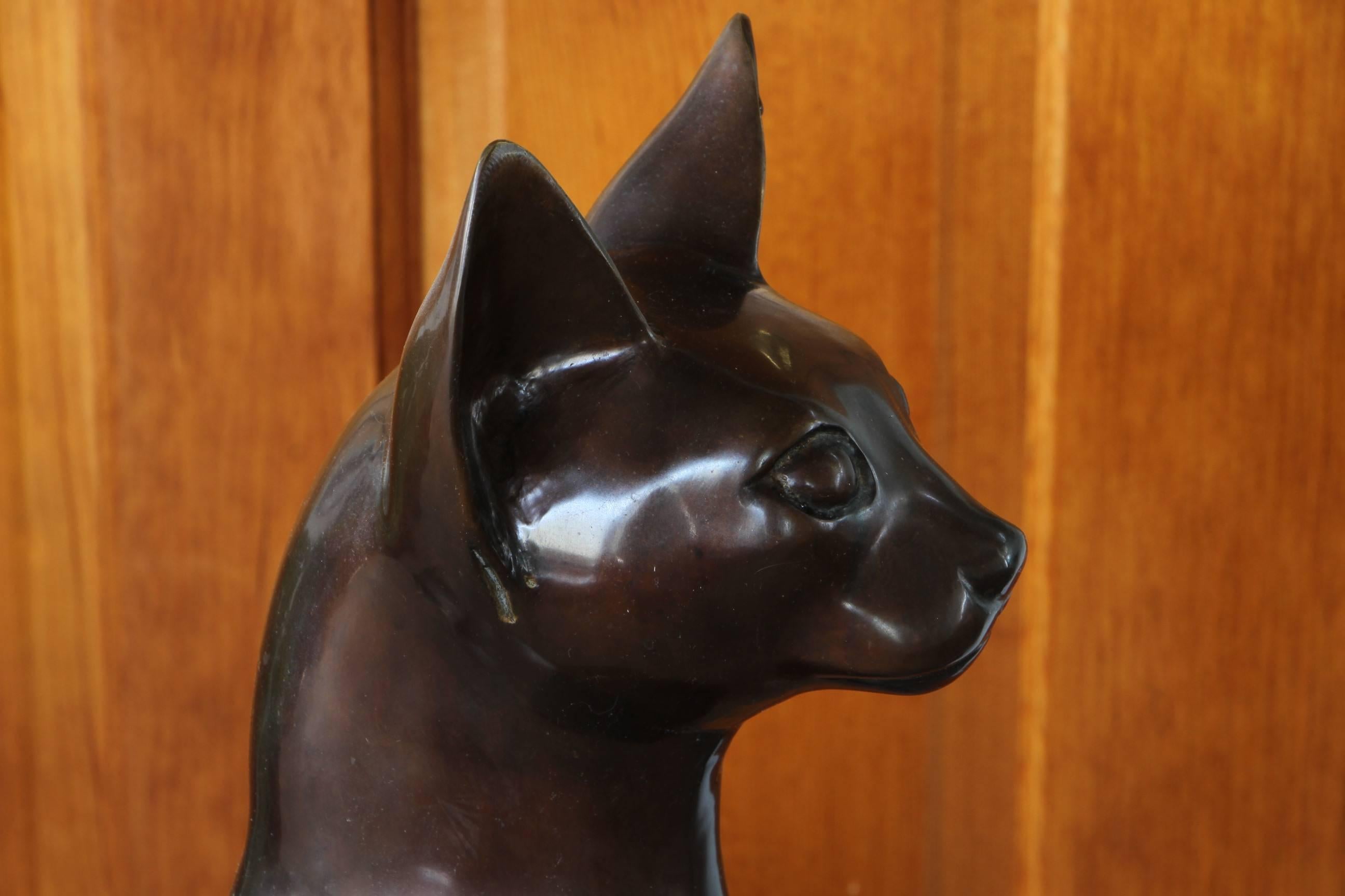 A very well made and cast brass or bronze sculpture of a seated cat in Egyptian style with fine dark patina.