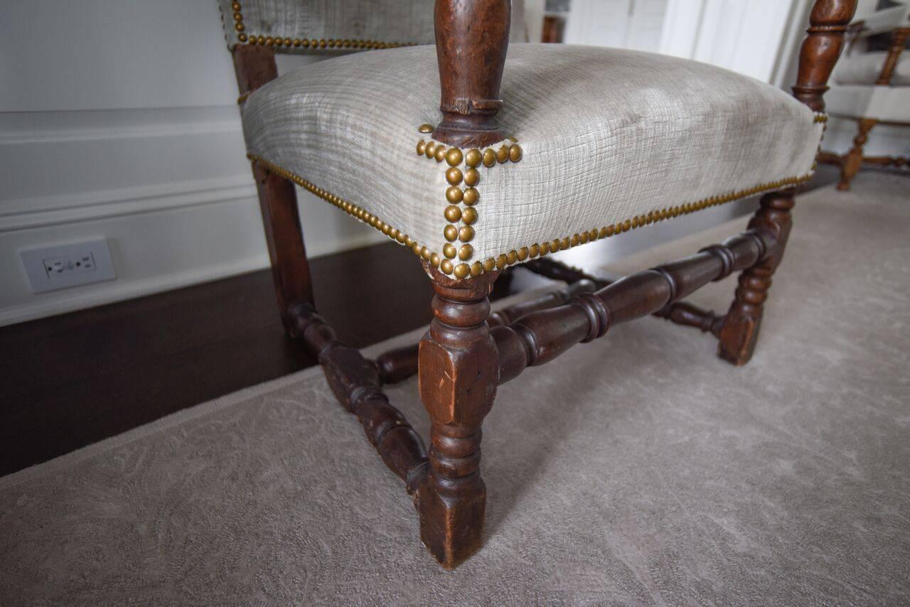 17th century sturdy walnut armchair with straight back and stretcher connecting legs. Very good condition, newly reupholstered. Arm height is 23.5