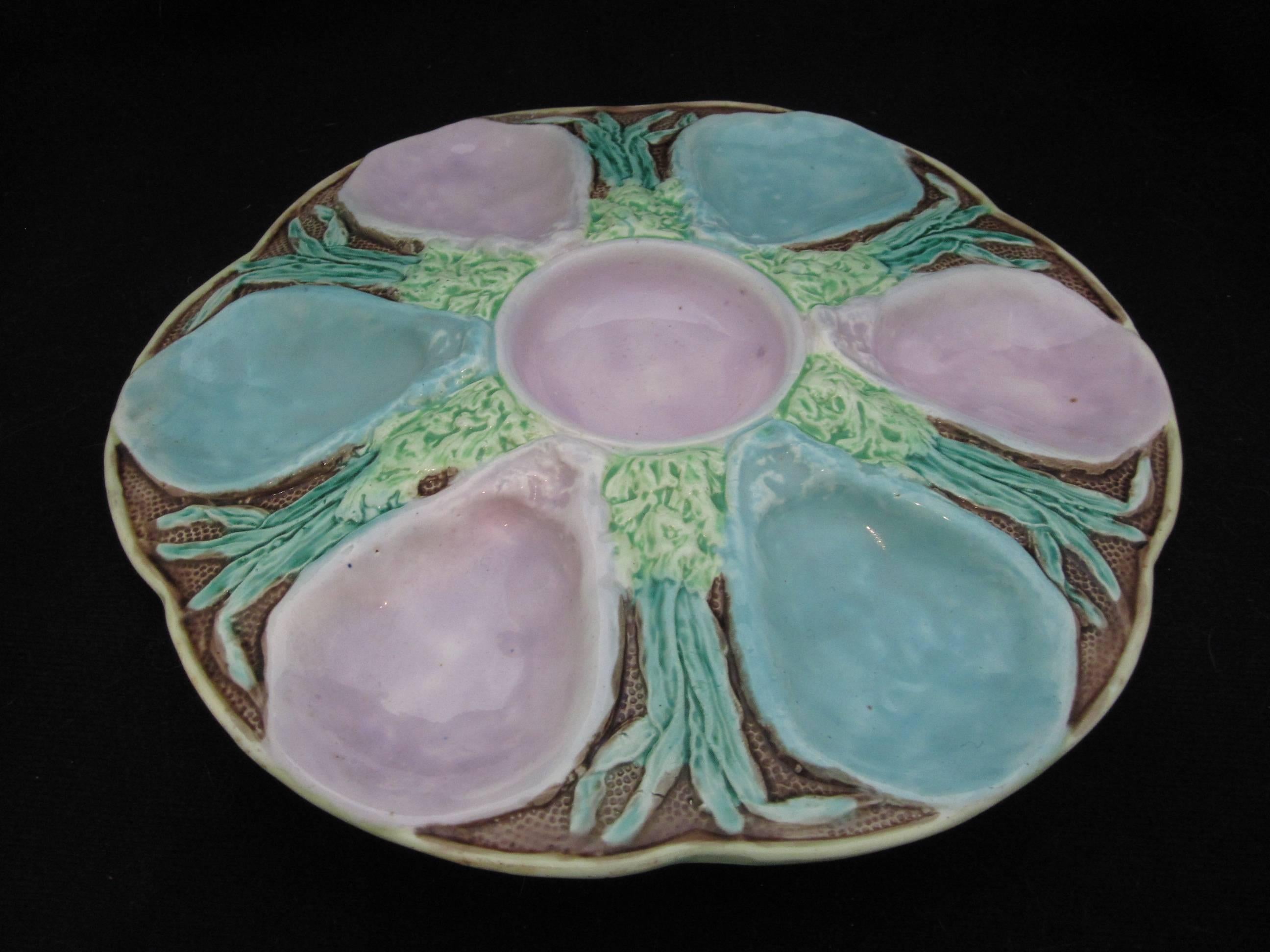 A Longchamps Majolica pottery oyster plate, France, mid-late 19th century. Highly dimensional with six wells alternating in turquoise and pink on a seaweed bed with a stippled ground. Mottled glazing to the verso. 

  